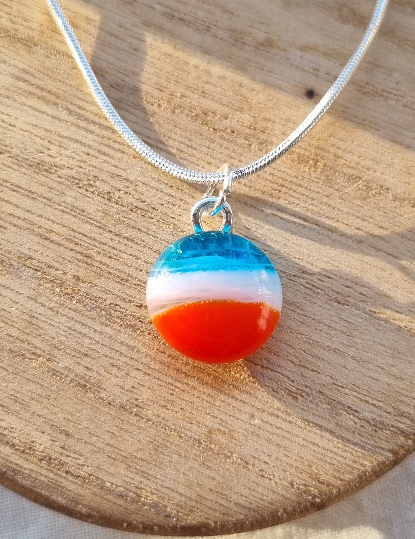 Blue, white and orange handmade glass pebble pendant.