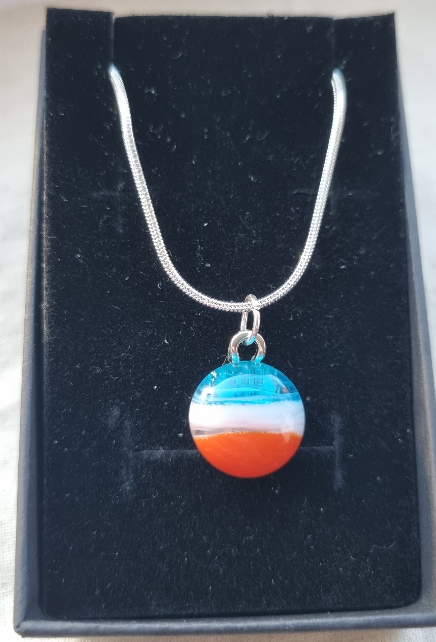 Blue, white and orange handmade glass pebble pendant.